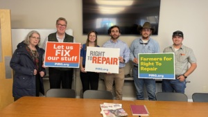 Six right to repair advocates holding signs that say "Let us fix our stuff," "Right to Repair," and "Farmers for Right to Repair."